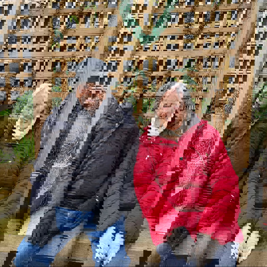 Two people sitting on a garden bench in winter clothing